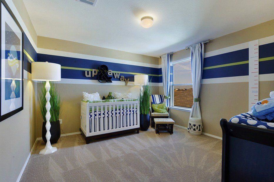Stylish nursery with beige armchair and white crib over carpet flooring. It is illuminated by gorgeous white floor lamps and flush mount light bringing a warm and cozy ambiance to the room.