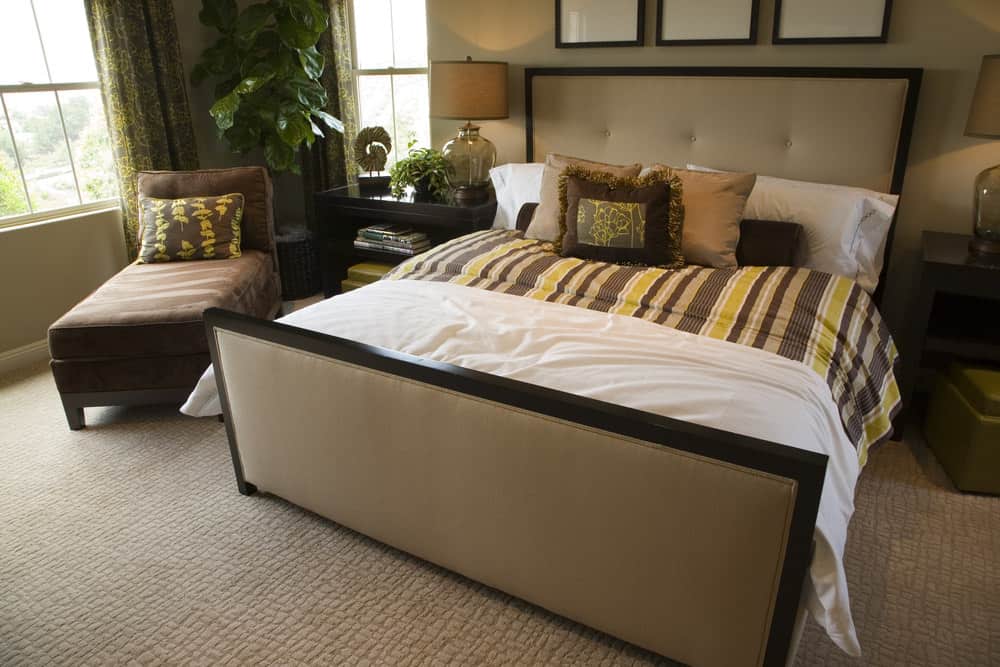 A focused look at this primary bedroom's large bed setup lighted by table lamps on both sides. The room features indoor plants inside the room.
