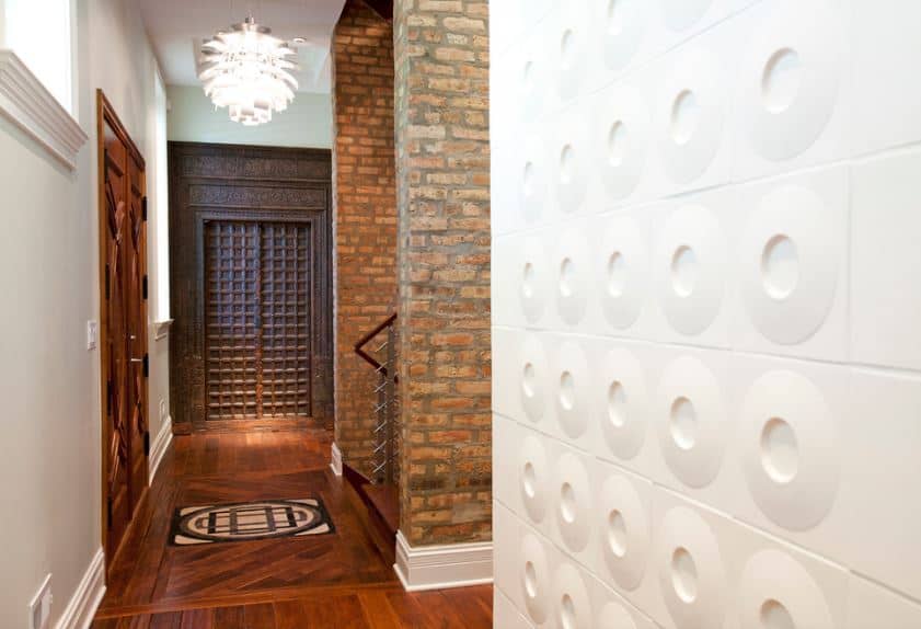 The intricate and elegant wooden main doors match with the hardwood flooring topped with a peculiar pendant light that brightens the foyer. Across from the door is the staircase that has two large pillars made of bricks on either side of it.