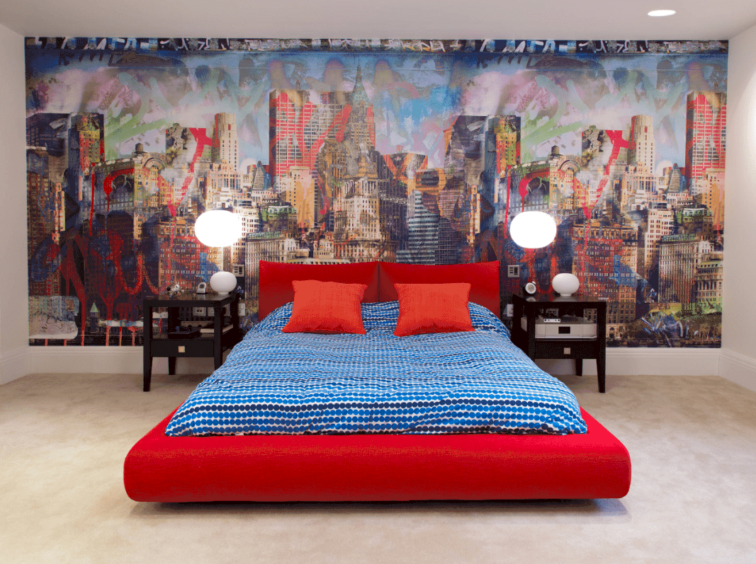 A large scale wall mural is the highlight of this sleek bedroom with dark wood nightstands and a red platform bed dressed in blue dotted bedding.
