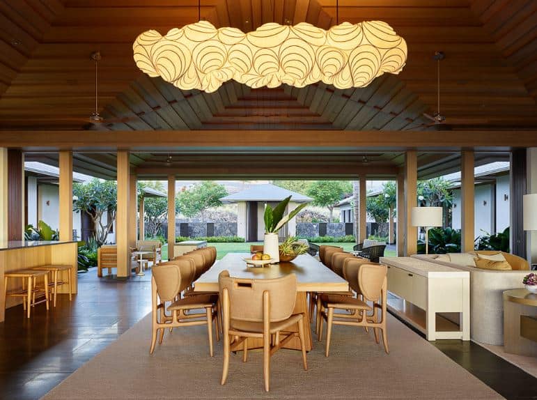 This dining area is in the middle of the living room area and the kitchen with the same arched wooden ceiling and dark hardwood flooring. The highlight of this dining area is the large decorative pendant light that looks like a cartoon cloud.