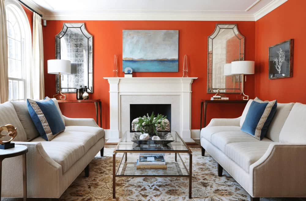 Traditional living room with a glass top coffee table and a white fireplace accented with an abstract painting. It includes a pair of gorgeous mirrors and facing sectionals that add perfect symmetry to the room.