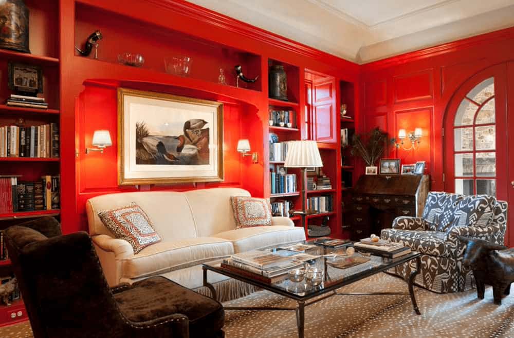 A framed artwork hangs above the beige sofa lighted by sconces and traditional floor lamp. This room has gorgeous seats and built-in shelving filled with books and decors.