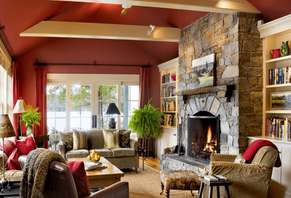 White built-in shelvings flank a stone fireplace in this rustic living room offering comfy seats and a wooden coffee table that sits on a jute area rug.