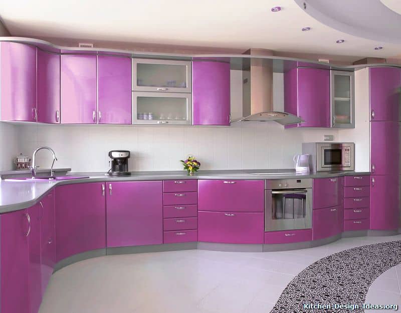 This modern kitchen has a large L-shaped peninsula with a unique curved finish mirrored by the floating cabinet. Both of these have purple cabinets and drawers with silver handles that match the stainless steel appliances.