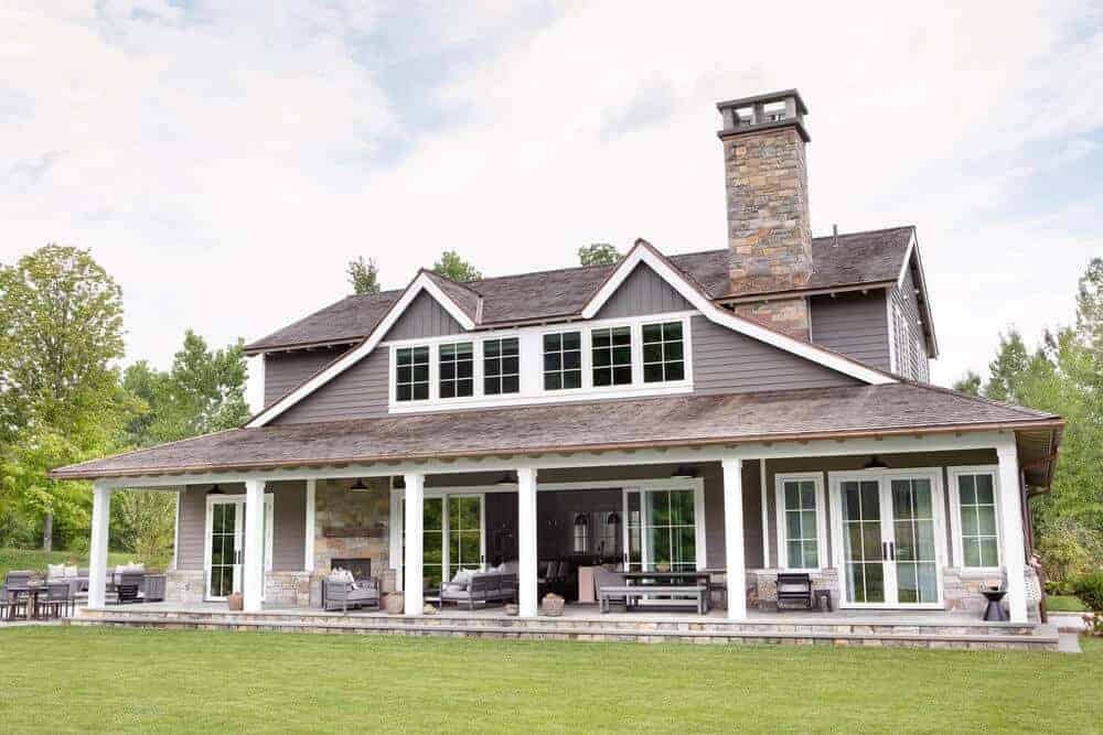 This backyard view of the house shows a lush and well-maintained lawn of grass that can be enjoyed from the various outdoor areas of the charming home like the sitting area with a stone fireplace and the dining area by the large glass sliding doors.