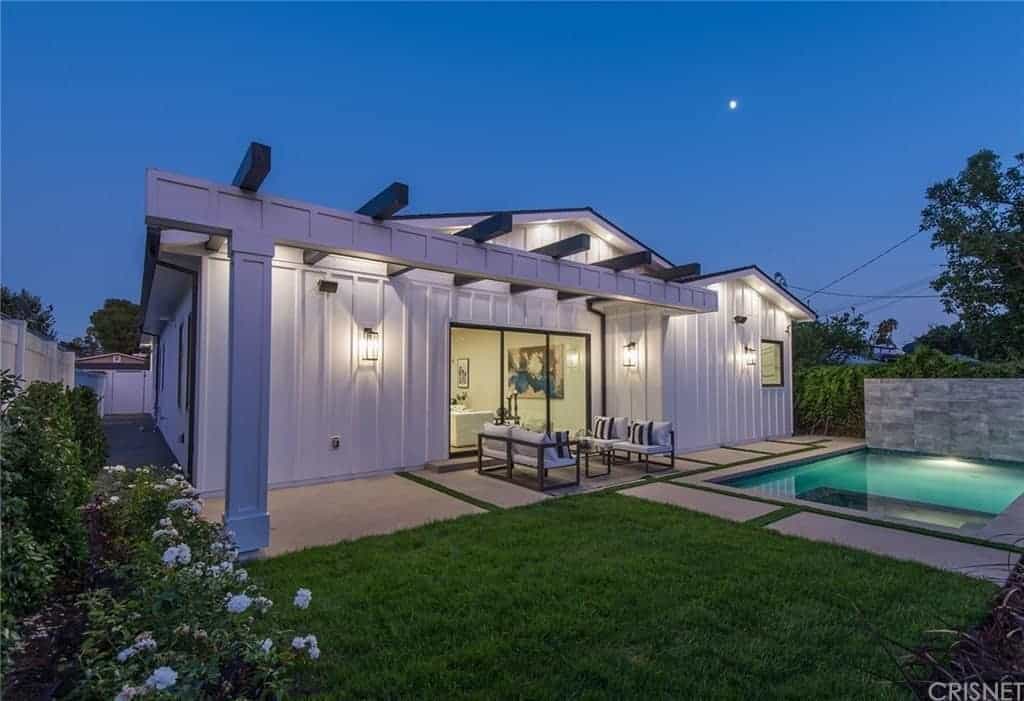 This backyard showcases the brilliantly lit swimming pool. Although it is small in size, it makes up with beauty. It has a concrete walkway surrounding it that has the same green accents as the driveway and can be enjoyed while on the sitting area that has cushioned furniture.