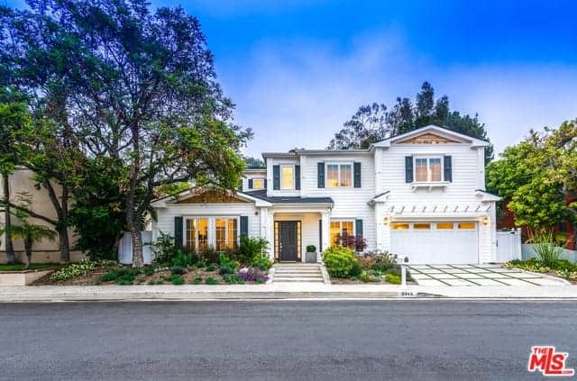 This charming landscaping enhances the aesthetic of the beautiful home. It has tall trees and shrubs evenly spaced on one side and on the other side of the stone steps is a small piece of lawn filled with shrubs that flank the concrete driveway.