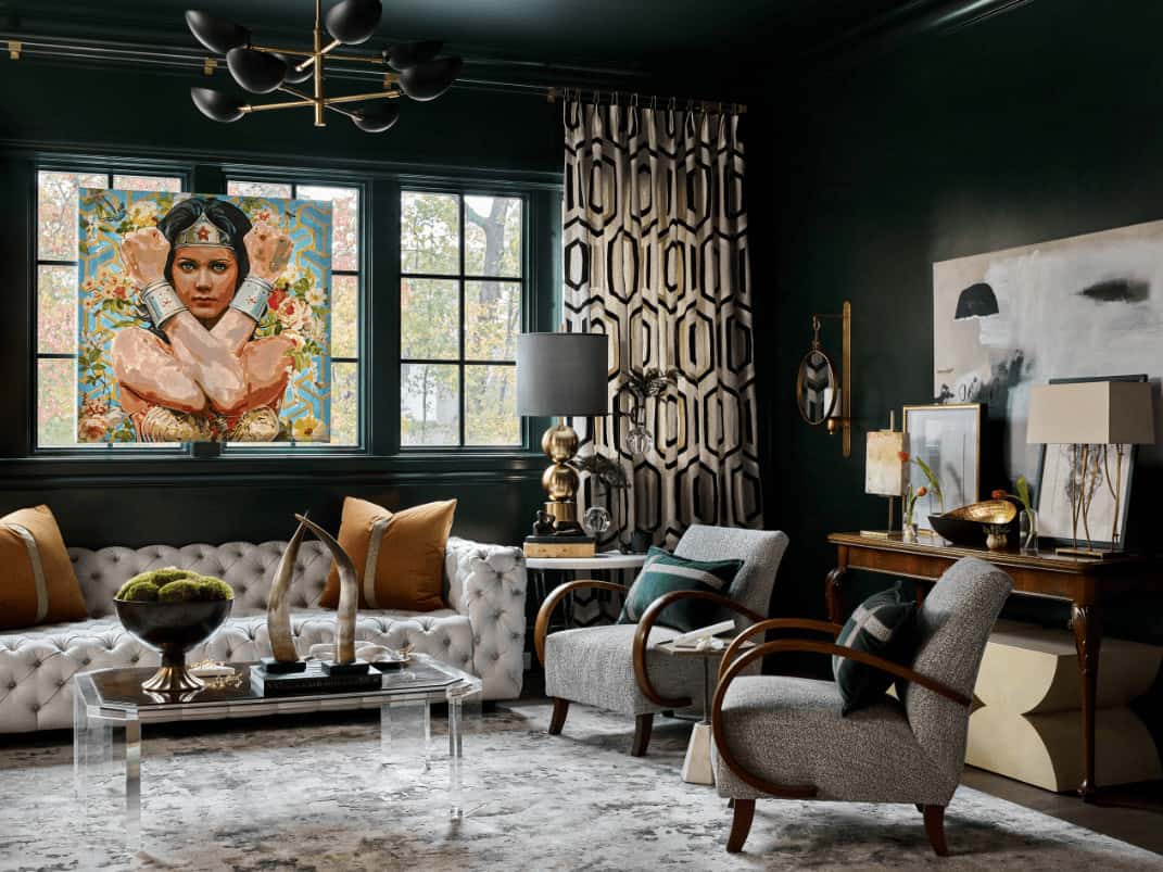 A gorgeous portrait stands out in this black living room with gray armchairs and a chesterfield sofa paired with a glass coffee table. It includes a contemporary chandelier and wooden console table topped with a sleek table lamp and framed photos.