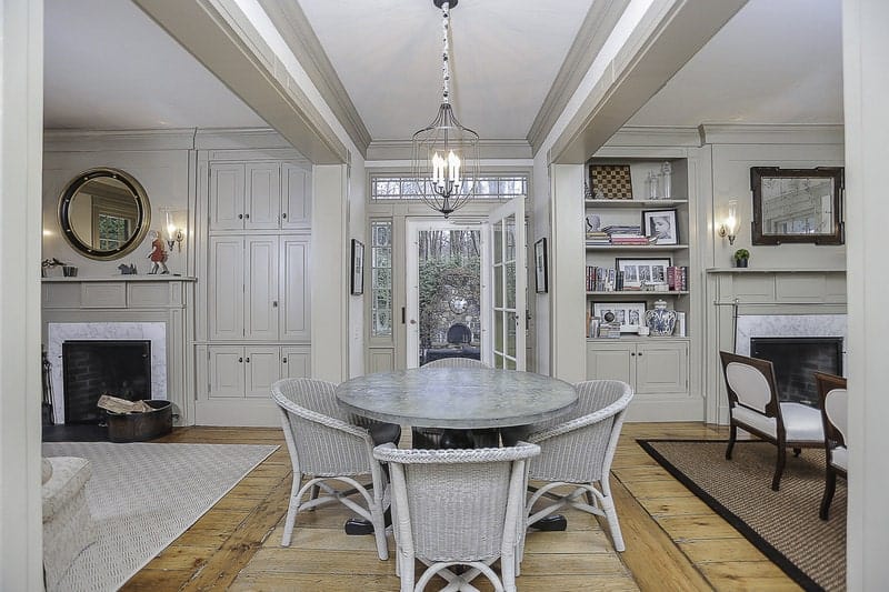 The rustic woven wicker dining chairs are painted with a light gray hue that matches with the gray surface of the round dining table with dark wooden legs that stand out against the hardwood flooring. This dining set also matches with the light gray ceiling and walls.