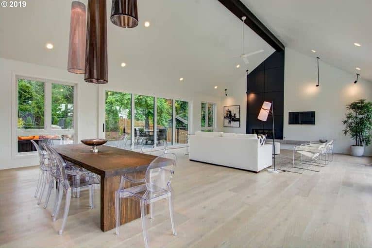 This simple dining area is part of a great room that also houses the living room area on the same light hardwood flooring that makes the wooden dining table stand out. This is complemented by its modern see through dining chairs.