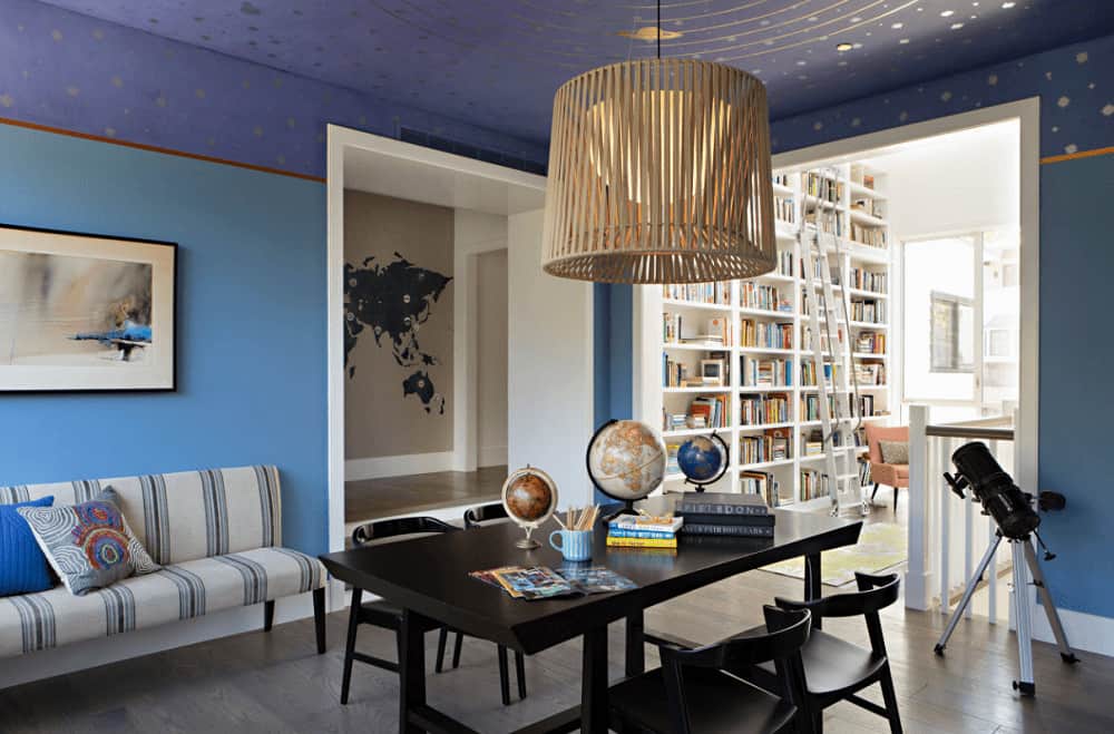 Blue living room boasts a striped sofa and a dark wood table with matching chairs over the natural hardwood flooring. It is lighted by an oversized pendant that hung from the solar system ceiling.
