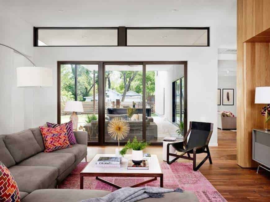 The medium-sized living room features a black chair and gray sectional accented with eye-catching pillows. It includes a wooden coffee table that sits on a pink area rug.